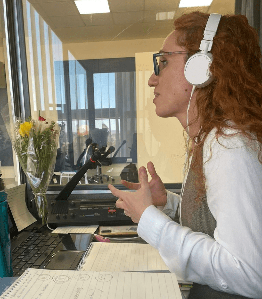 Imagen de Sara the Interpreter en acción, gesticulando y comunicando con energía durante una interpretación presencial. La escena en una cabina de interpretación onsite resalta su profesionalismo y habilidad para facilitar la comunicación multilingüe.