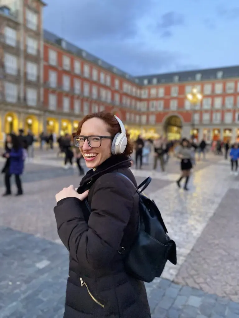 Sara sonriendo con cascos en medio de la Plaza Mayor de Madrid